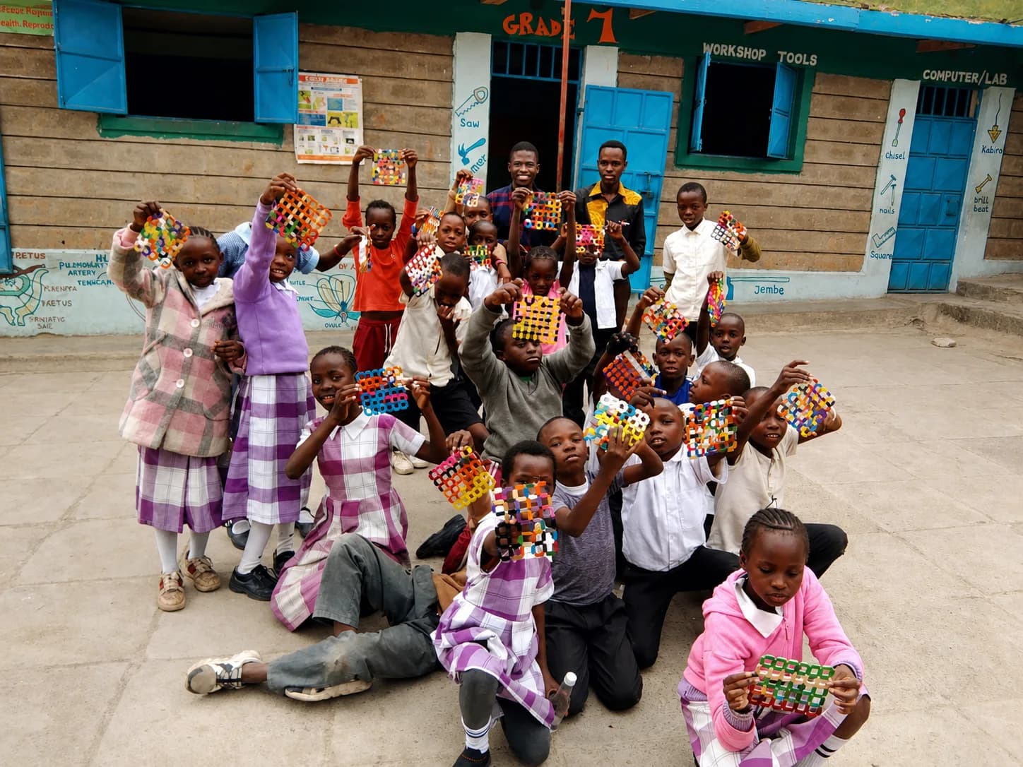 Little Bells learners proudly showing handmade beadwork outside their school